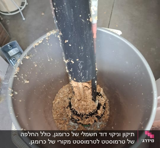 צינור שחור עם משקעים בתוך דלי אפור